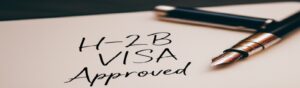 A fountain pen resting on a document labeled "H-2B Visa Approved"