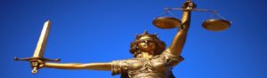 Estatua de la Diosa de la Justicia con los ojos vendados, sosteniendo una balanza y una espada, representando la imparcialidad legal y la justicia.
