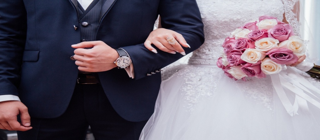 Newlywed couple walking arm in arm, with the bride holding a flower bouquet—symbolizing love and a new immigration journey.