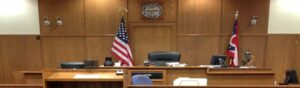 An empty U.S. courtroom with an American flag, symbolizing the legal vacuum and constitutional strain triggered by Trump’s 2025 immigration policies.