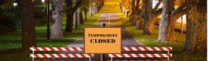A park gate with a "temporarily closed" sign and closure markers, symbolizing halted services during the 2025 U.S. government shutdown.