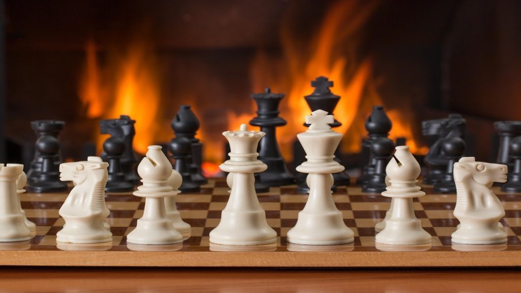 A chessboard with white and black pieces against a fiery background, representing strategy, foresight, and competitive decision-making.