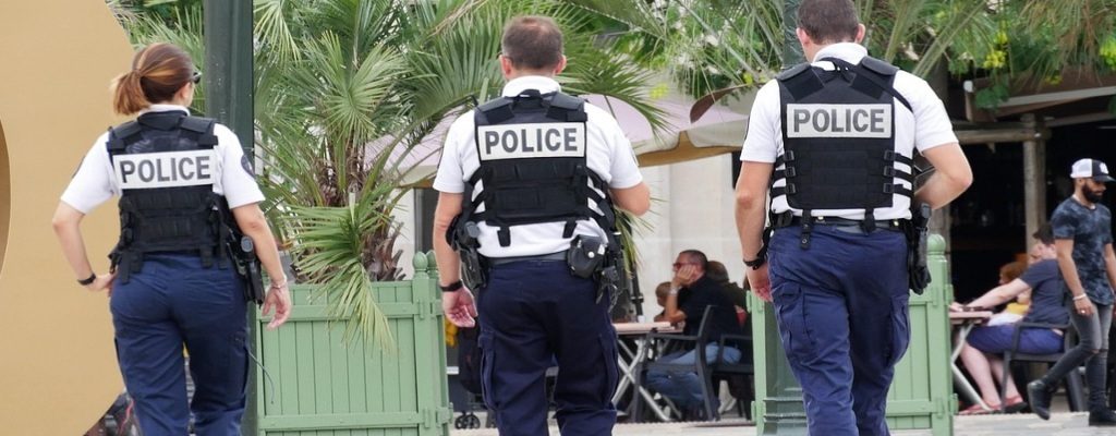 Three officers with “Police” on their backs walking toward seated individuals, showing immigration enforcement related to U.S. Immigration Visa controls.