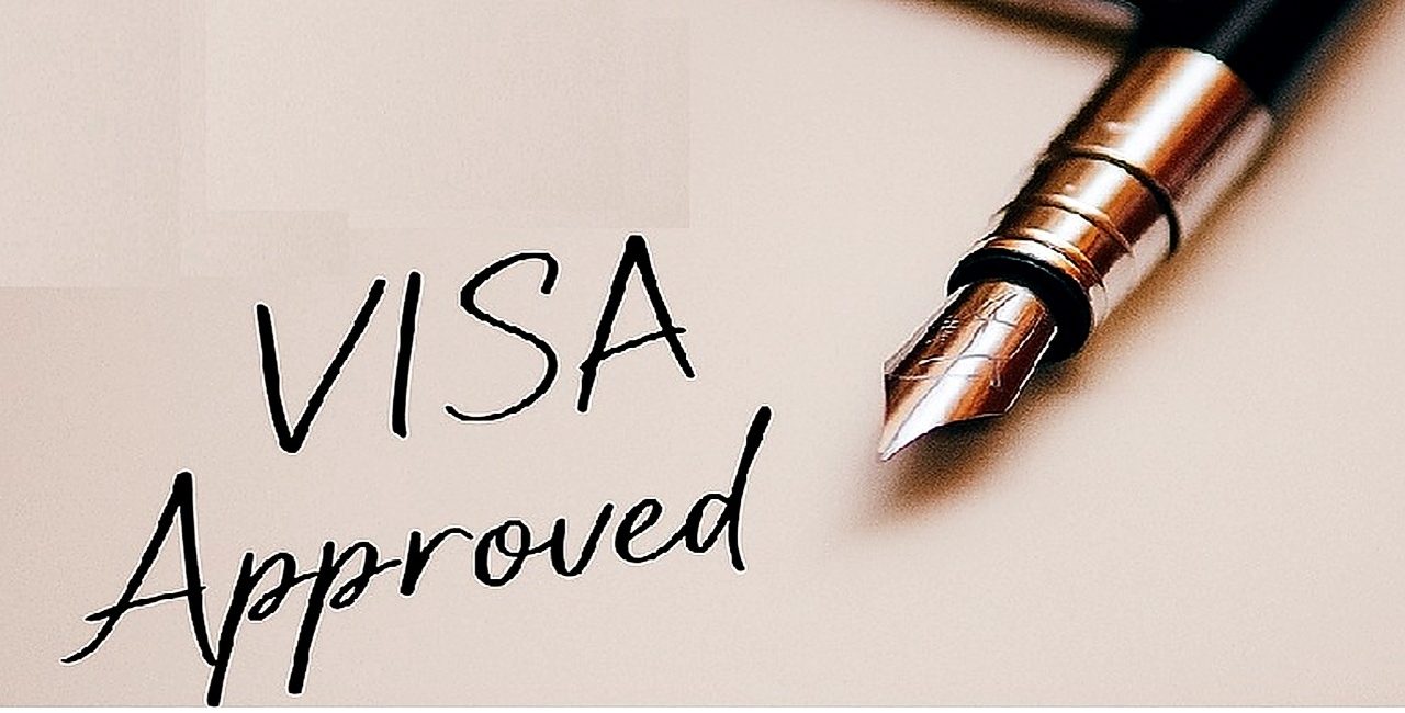 Primer plano de un documento con “Visa Approved” escrito con una pluma fuente y un sello de visa de inmigración de EE. UU.