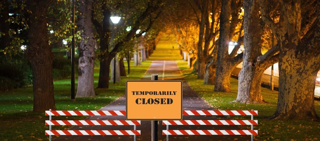 A park gate with a "temporarily closed" sign and closure markers, symbolizing halted services during the 2025 U.S. government shutdown.