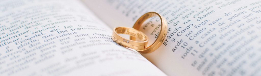 Wedding rings placed on a book about the Green Card process, symbolizing marriage-based immigration.